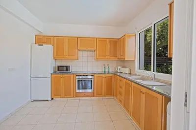 a kitchen with wooden cabinets and a white refrigerator at Villa Protaras Eos, Modern 3Bdr Protaras Villa With Pool, Short Walk in Protaras