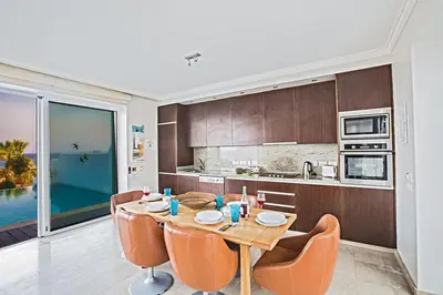 a kitchen with a wooden table and chairs in a kitchen at Villa Fig Tree Bay Seafront, Luxury 5Bdr Seafront Protaras in Protaras