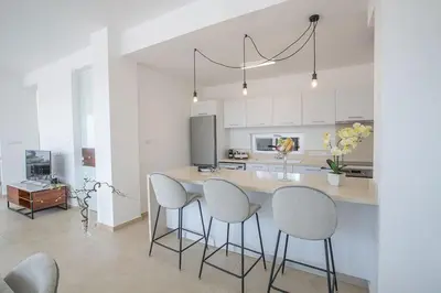 a kitchen with white cabinets and a island with stools at Villa Olive Thalassa, Brand New, Luxury 3Bdr Protaras Villa With Private Pool in Protaras