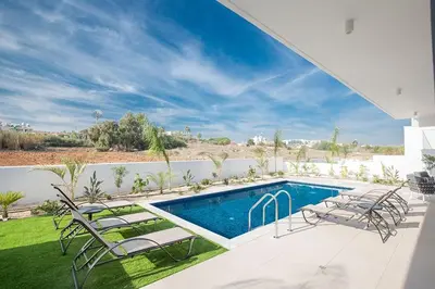 a swimming pool in a yard with chairs and a swimming pool at Villa Olive Thalassa, Brand New, Luxury 3Bdr Protaras Villa With Private Pool in Protaras