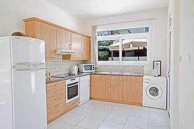a kitchen with wooden cabinets and a white refrigerator at Villa Dafnis Chrysos - Modern 3 Bedroom Protaras Villa With Pool in Protaras