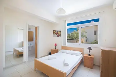 a bedroom with a bed and a bathroom with a window at Villa Dafnis Chrysos - Modern 3 Bedroom Protaras Villa With Pool in Protaras
