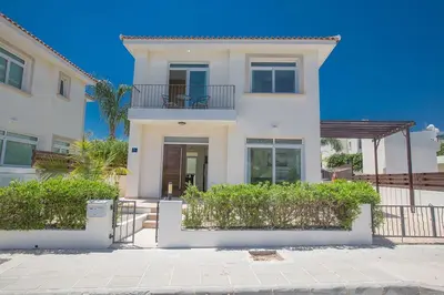a white house with a balcony and bushes at Villa Dafnis Chrysos - Modern 3 Bedroom Protaras Villa With Pool in Protaras