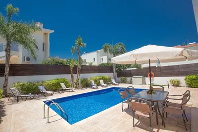 a pool with chairs and a table and an umbrella at Villa Dafnis Chrysos - Modern 3 Bedroom Protaras Villa With Pool in Protaras