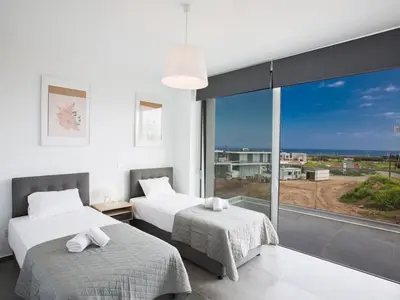 two beds in a room with a large window at Villa Olive Platinum, New And Luxury 4Bdr Protaras Villa With Private Pool in Protaras