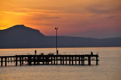 a pier with people fishing on the water at sunset at Villa Leoforos Dyo, Modern 3Bdr Protaras Villa With Pool, In The Centre in Protaras