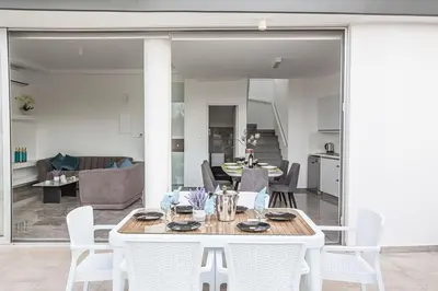 a dining room with a white table and chairs at Villa Olive Gold, Luxury And Brand New 2Bdr Protaras Villa With Private Pool in Protaras