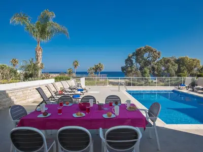 a table with a purple table cloth next to a swimming pool at Villa Mesogi Seafront, Stunning 4Bdr Fontline Protaras in Protaras