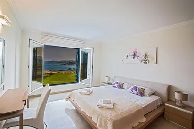 a white bedroom with a bed and a large window at Villa Fig Tree Bay Frontline,Luxury 4Bdr Sea-Front Protaras Villa With Pool in Protaras