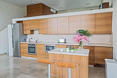 a kitchen with wooden cabinets and a kitchen island with flowers at Villa Fig Tree Bay Frontline,Luxury 4Bdr Sea-Front Protaras Villa With Pool in Protaras