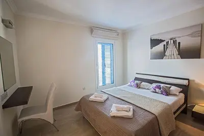 a bedroom with a bed and a chair and a window at Villa Fig Tree Bay Frontline,Luxury 4Bdr Sea-Front Protaras Villa With Pool in Protaras