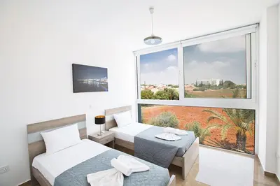 a bedroom with two beds and a large window at Villa Manta Platina - Brand New Luxury 3 Bedroom Protaras Villa in Protaras