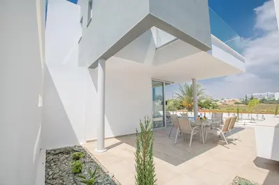 a white house with a table and chairs on a patio at Villa Manta Platina - Brand New Luxury 3 Bedroom Protaras Villa in Protaras