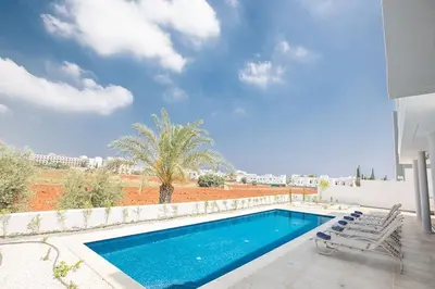 a swimming pool with chairs next to a house at Villa Manta Platina - Brand New Luxury 3 Bedroom Protaras Villa in Protaras