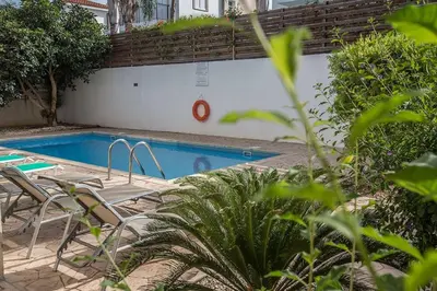 a swimming pool with chairs next to a building at Villa Dafnis Sunshine - Modern 3 Bedroom Central Protaras Villa With Pool in Protaras