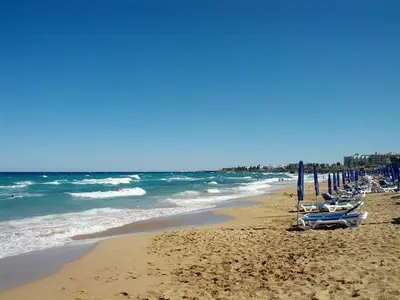 a beach with several umbrellas and the ocean at Villa Dafnis Sunshine - Modern 3 Bedroom Central Protaras Villa With Pool in Protaras