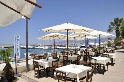 a restaurant with white tables and umbrellas at Villa Dafnis Sunshine - Modern 3 Bedroom Central Protaras Villa With Pool in Protaras
