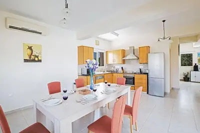 a kitchen with a white dining table and chairs at Villa Akefalo - Beautiful 3 Bedroom Protaras Villa With Private Pool in Protaras