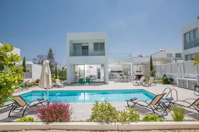 a villa with a swimming pool and chairs at Villa Ochosto Helios - Beautiful 5 Bedroom Protaras Villa - Walking Distance in Protaras