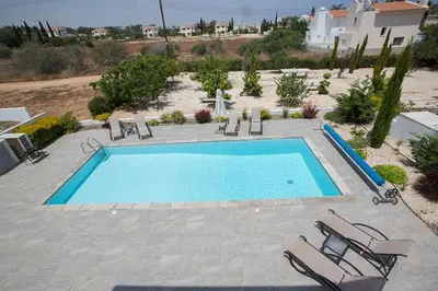 a large swimming pool with chairs at Villa Ochosto Helios - Beautiful 5 Bedroom Protaras Villa - Walking Distance in Protaras