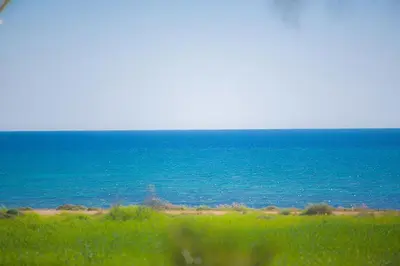 a view of the ocean from a field with green grass at Villa Adaman - Stunning 3 Bedroom Seafront Villa With Pool - Close To The Beach in Ayia Napa