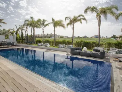 a swimming pool with chairs and palm trees at Villa Papadopo - Luxury 3 Bedroom Villa With Private Pool, Hot Tub And Sea Views in Paralimni