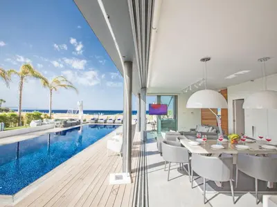 a dining room with a swimming pool and a house at Villa Papadopo - Luxury 3 Bedroom Villa With Private Pool, Hot Tub And Sea Views in Paralimni