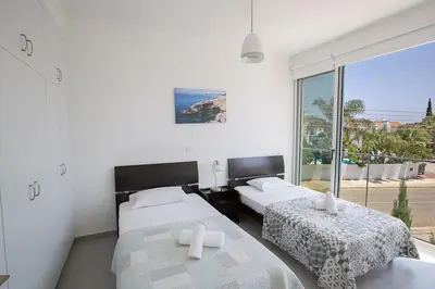 a bedroom with two beds and a large window at Villa Ochosto Chrysos - Stunning 5 Bedroom Protaras Villa - Close To Fig Tree in Protaras