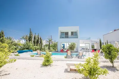 a white house with a swimming pool and chairs at Villa Ochosto Chrysos - Stunning 5 Bedroom Protaras Villa - Close To Fig Tree in Protaras