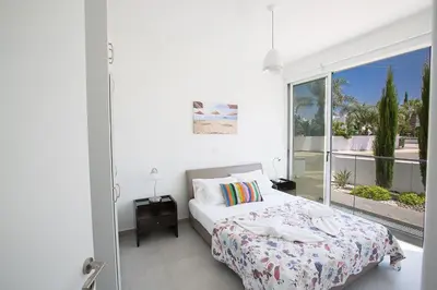 a white bedroom with a bed and a large window at Villa Ochosto Chrysos - Stunning 5 Bedroom Protaras Villa - Close To Fig Tree in Protaras