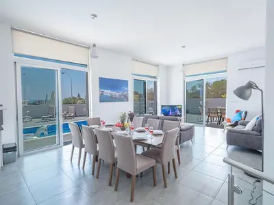 a dining room and living room with a table and chairs at Villa Protaras Miramar, Luxury And New 5Bdr Protaras Villa With Pool in Protaras