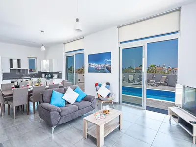 a living room with a couch and a table and a tv at Villa Protaras Miramar, Luxury And New 5Bdr Protaras Villa With Pool in Protaras