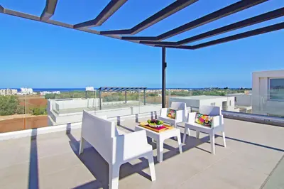 a patio with white chairs and a table on a balcony at Villa Nova in Protaras