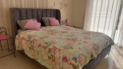 a bedroom with a large bed with pink pillows at Nissi 3 Pool Access Garden Apartment in Ayia Napa