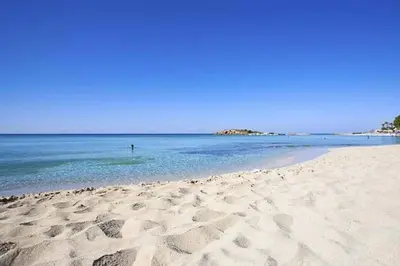 a person standing in the water on a beach at Nissi 3 Pool Access Garden Apartment in Ayia Napa