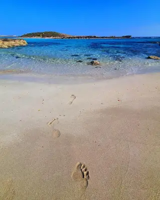 a pair of footprints in the sand on a beach at Nissi 3 Pool Access Garden Apartment in Ayia Napa