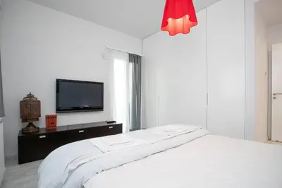 a white bedroom with a bed and a tv at Mayra Seafront Luxury Apartment (BREAKBOOKING-CY) in Limassol