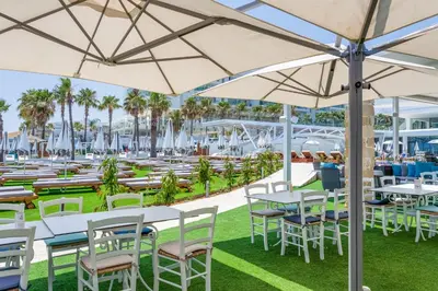 an outdoor patio with tables and chairs and umbrellas at Flamingo Paradise Beach Hotel - Adults Only in Protaras
