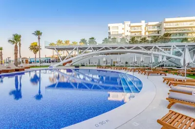 a bridge over a swimming pool with benches and buildings at Flamingo Paradise Beach Hotel - Adults Only in Protaras