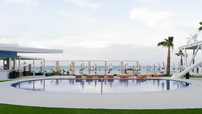 a swimming pool with chairs and the ocean in the background at Flamingo Paradise Beach Hotel - Adults Only in Protaras