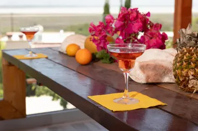 two glasses of wine on a table with flowers at LIMASSOL AKROTIRI BEACH VINE COTTAGE a in Limassol