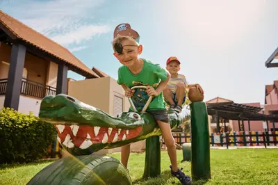 two young boys riding on a dinosaur slide at ROBINSON Cyprus in Alaminos
