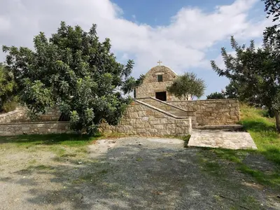 an old stone building with a church behind a stone wall at Rothkia's Home in Parekklisha