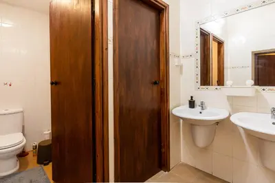 a bathroom with a toilet and a sink and a wooden door at Bee Hostel in Limassol