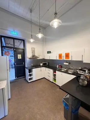 a kitchen with white cabinets and a black counter top at Bee Hostel in Limassol