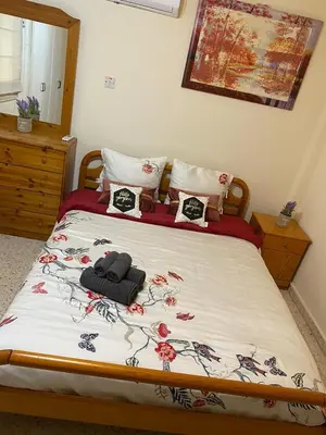 a bedroom with a bed with a floral bedspread at Larnaca Comfort Rooms With Smart TV & Netflix in Larnaka