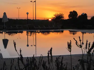 a pool of water with a sunset in the background at Protaras Tennis and Country Club in Protaras