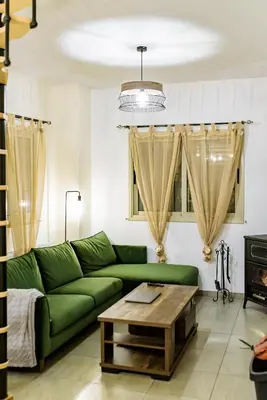 a living room with a green couch and a coffee table at Aprosmeno Jacuzzi House 2 in Agros