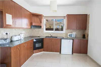 a kitchen with wooden cabinets and a white appliance at Carilisto Villas Big 4 Bedrooms in Center of Ayia Napa in Ayia Napa