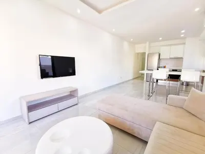 a living room with a couch and a tv on a wall at Vasilo Court Seaview City Apartment in Larnaka